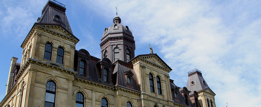 A photo of the exterior of the legislative assembly. The camera is pointing upwards, focusing on the dome on top of the building.